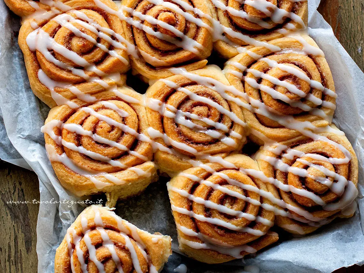 A close-up shot of freshly baked cinnamon rolls drizzled with white icing.