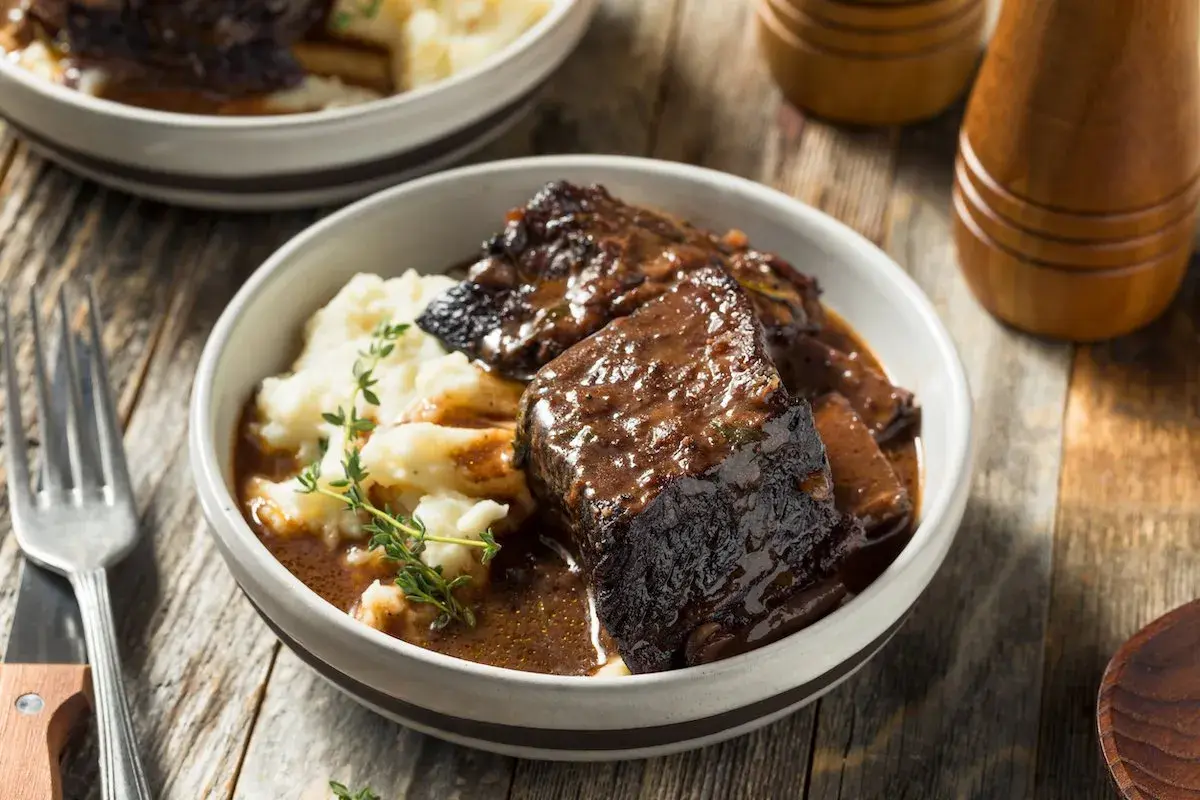 Un succulento brasato di manzo servito con purè di patate e guarnito con timo fresco.