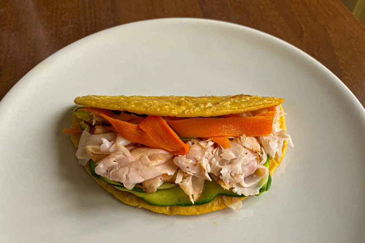 Piadina di ceci ripiena di tacchino sfilacciato, zucchine e carote a julienne. Un pasto leggero e gustoso.