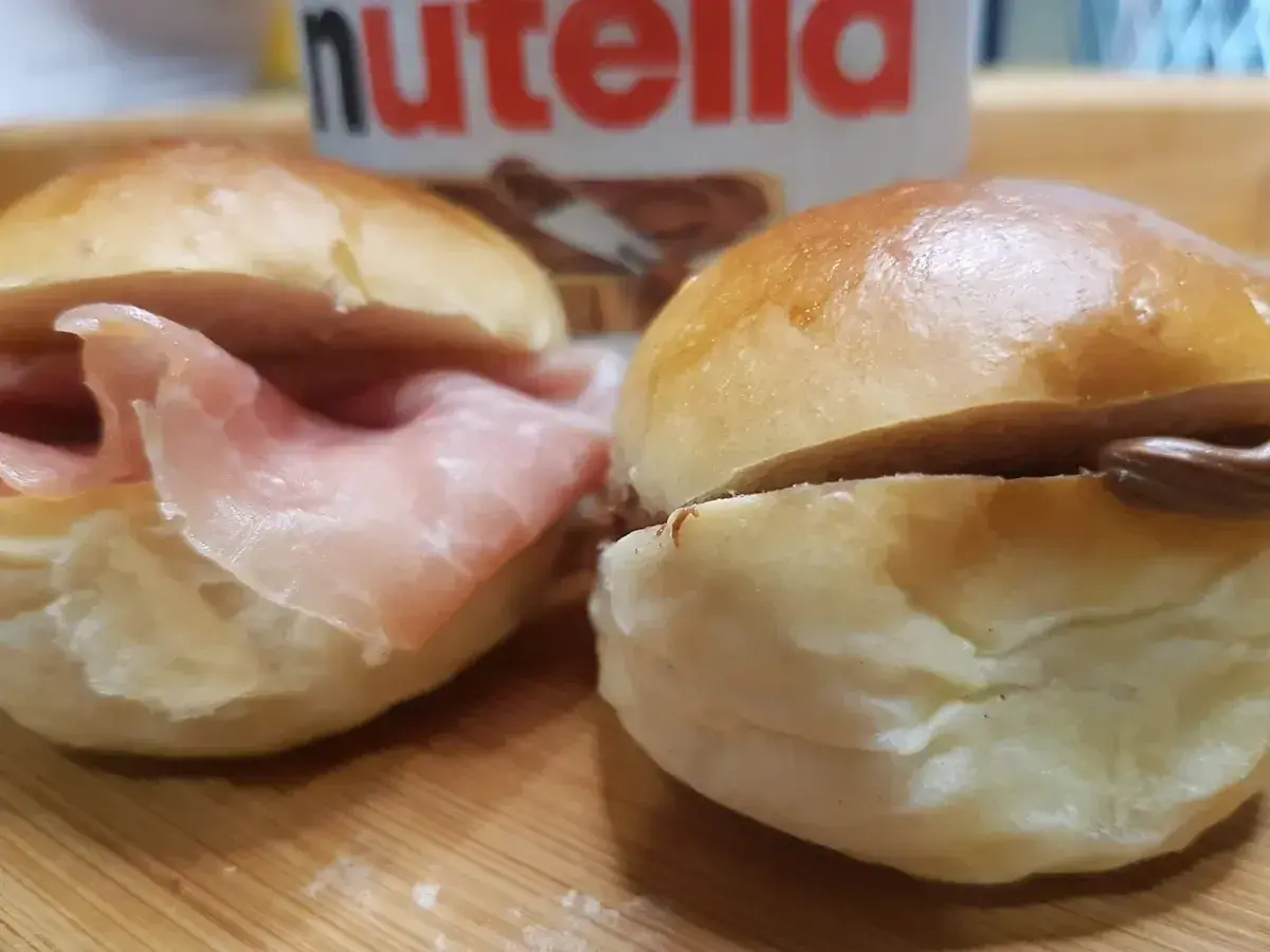 Due panini al latte, uno con prosciutto e l'altro con Nutella, pronti per essere gustati.