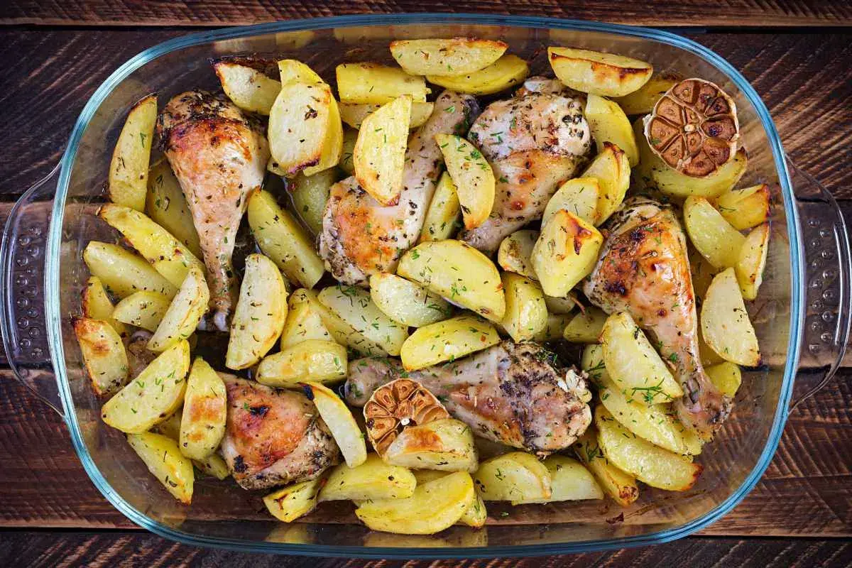 Un succulento pollo e patate al forno, dorati e profumati, in una teglia di vetro.