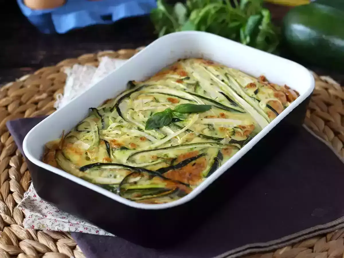 Deliziosa frittata di zucchine al forno, dorata e profumata, guarnita con basilico fresco.