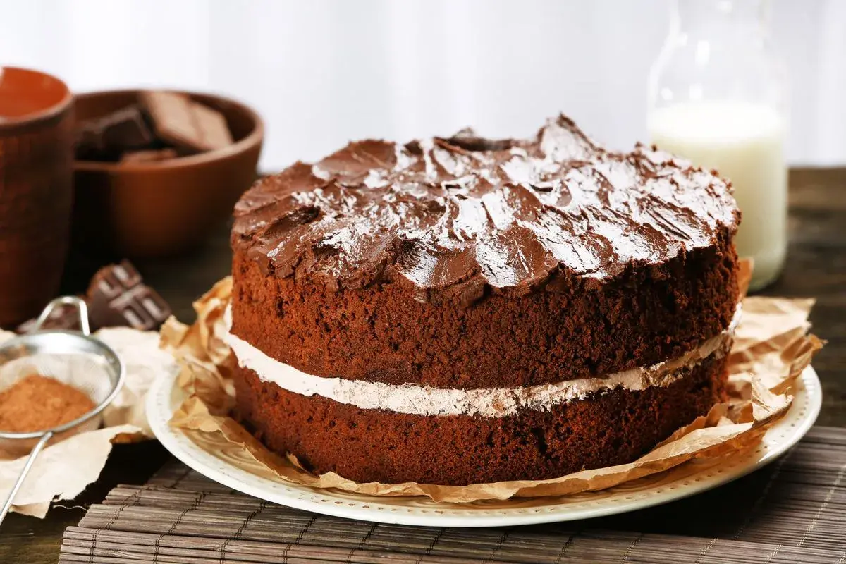 Torta al cioccolato a due strati, con glassa e zucchero a velo, che ricorda una torta Kinder Delice fatta in casa.