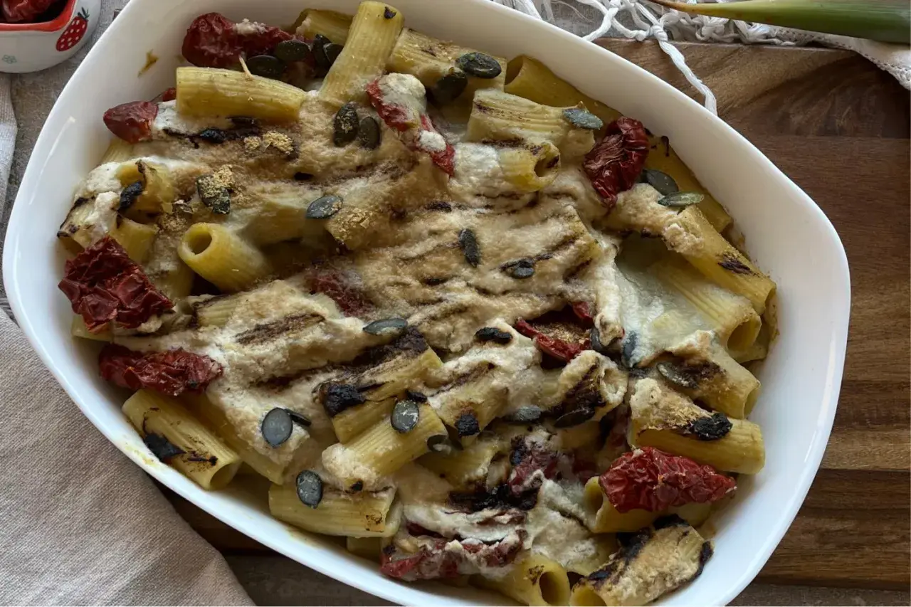Piatto di pasta con carciofi alla siciliana, pomodori secchi e semi di zucca, gratinata al forno.