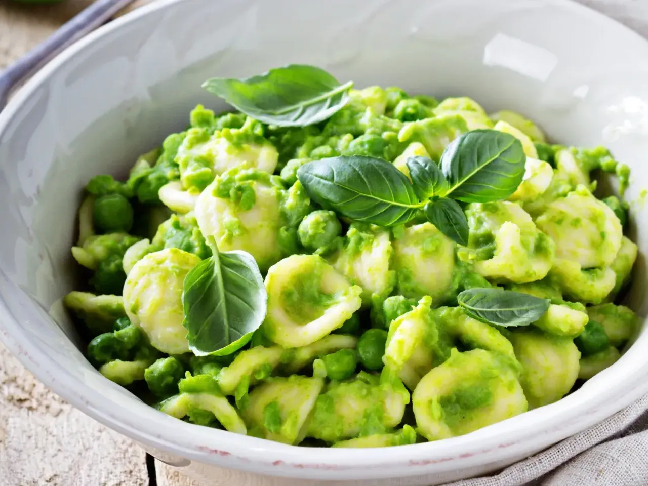 Orecchiette fatte in casa con crema di piselli e basilico fresco, un piatto primaverile invitante.
