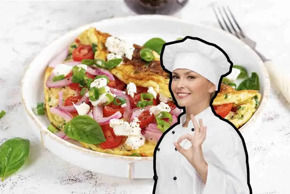 Chef sorridente mostra una deliziosa frittata di cipolle, pomodori e formaggio feta, guarnita con basilico fresco.