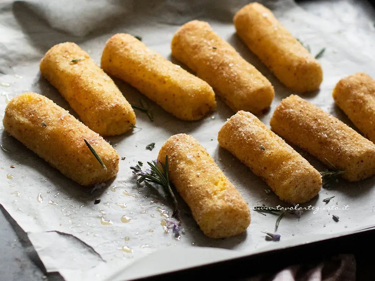 Crocchette di patate al forno dorate e croccanti, pronte per essere gustate. Profumano di rosmarino e sale grosso.