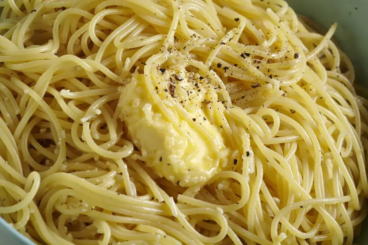 Spaghetti fumanti con una generosa porzione di burro fuso e pepe nero macinato fresco, un classico cacio e pepe pronto da gustare.