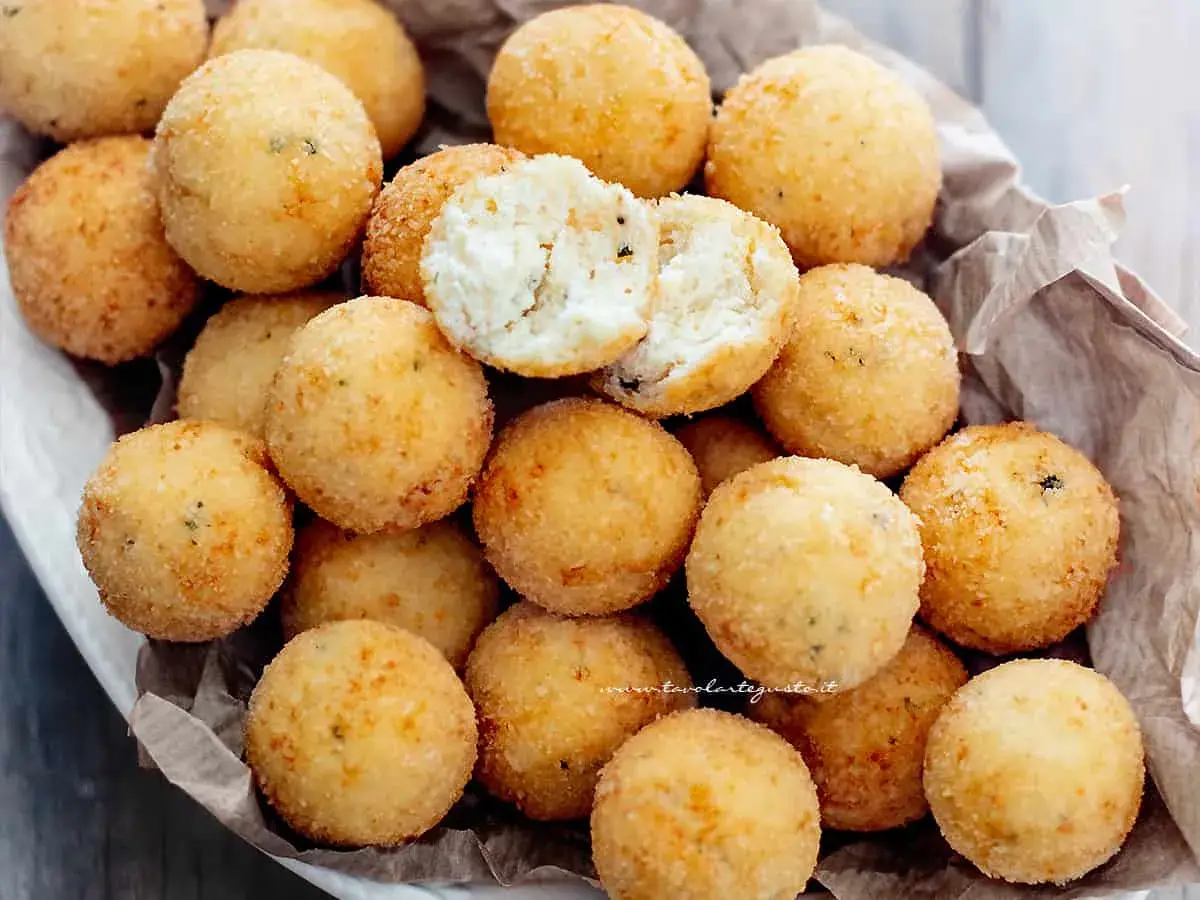 Un cesto pieno di croccanti polpette di ricotta, dorate e invitanti. Una è aperta, mostrando il morbido interno.