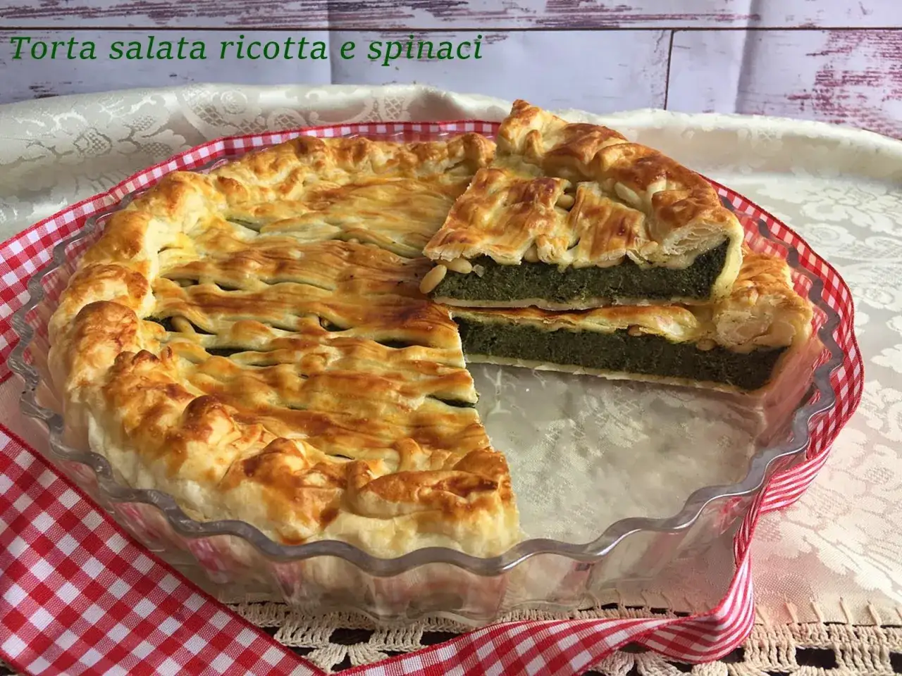 Torta salata ricotta e spinaci dorata e invitante, con una fetta tagliata che rivela il ripieno verde.