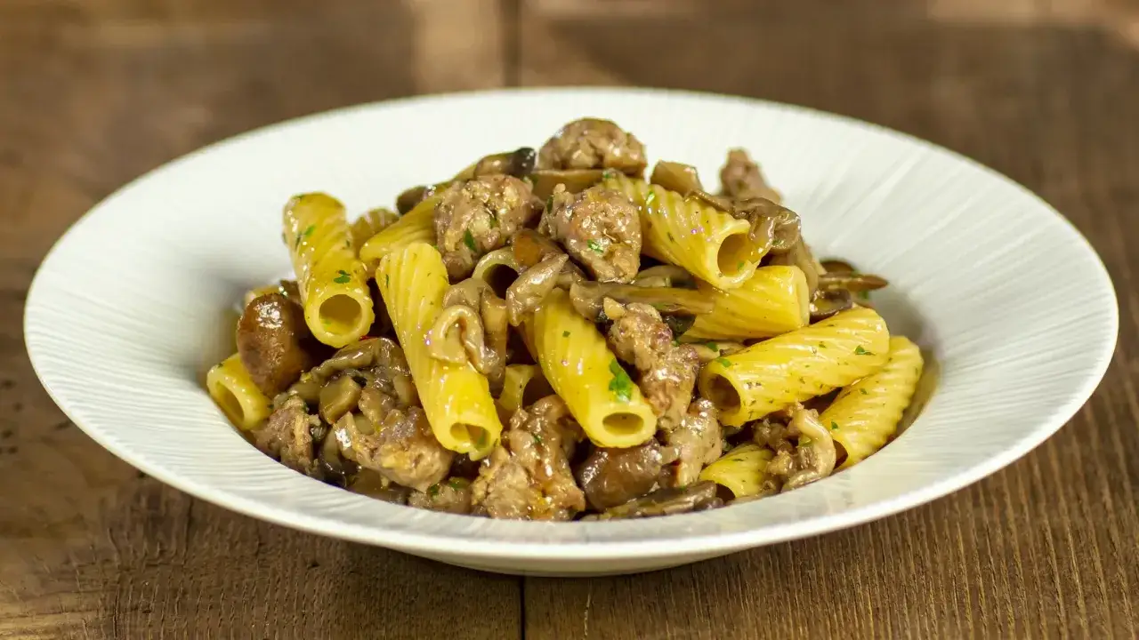 Piatto di pasta con funghi e salsiccia, un classico saporito.