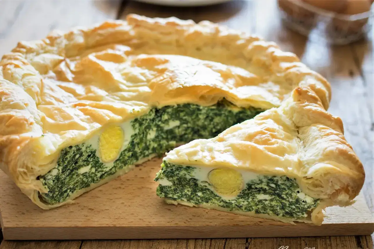 Torta Pasqualina con pasta sfoglia pronta: un guscio dorato racchiude un ripieno verde di spinaci e ricotta con uova intere.