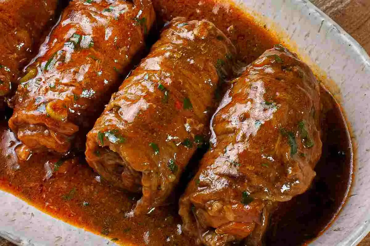 Involtini di carne in padella con sughetto, un piatto succulento e profumato, pronto per essere gustato.