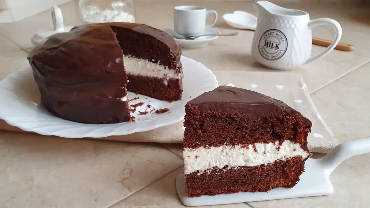 Una golosa torta Kinder Delice, con soffice pan di Spagna al cacao, farcita di crema bianca e ricoperta di cioccolato fondente.