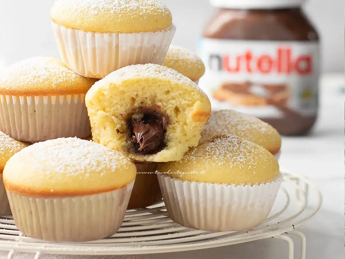 Muffin semplici con cuore morbido di Nutella, spolverati di zucchero a velo. Una ricetta golosa per un dolce perfetto.