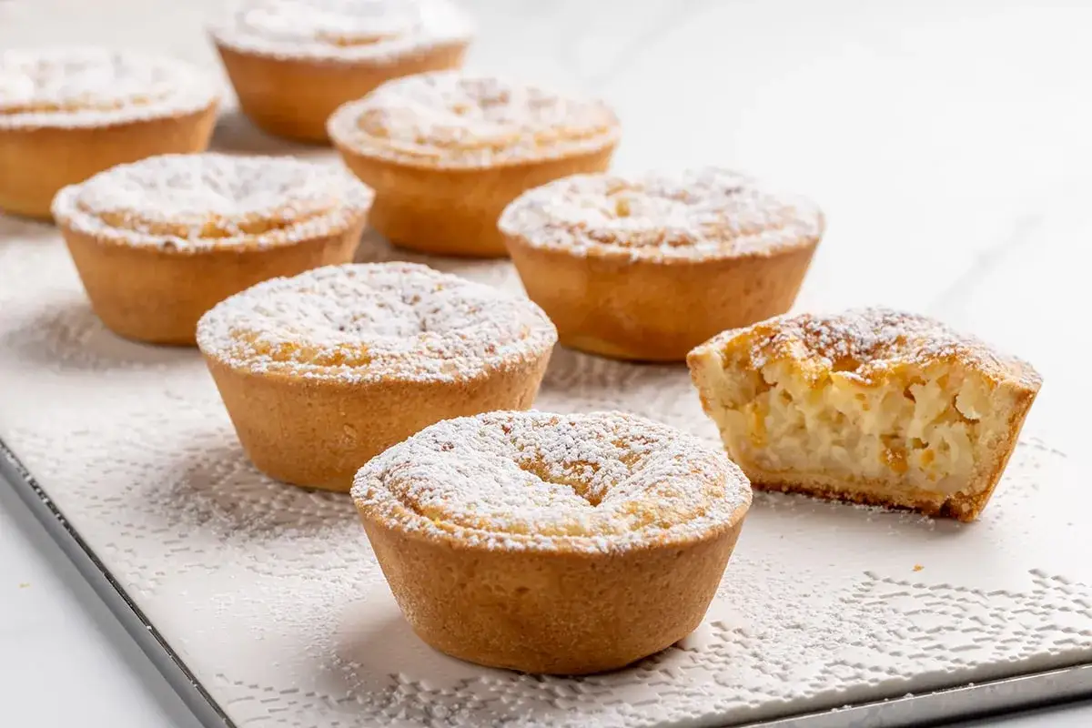 Deliziosi dolci da fare in casa, crostatine con ripieno cremoso e una spolverata di zucchero a velo.