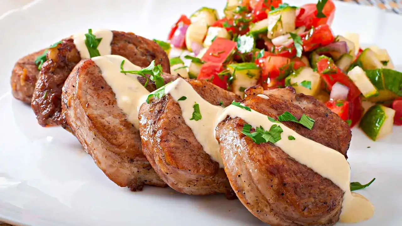 Delizioso spezzatino di maiale con salsa cremosa e un contorno fresco di pomodori e cetrioli.