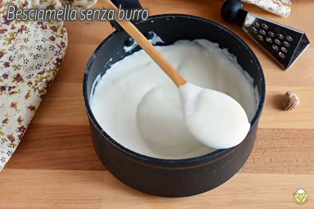 Besciamella senza burro cremosa in pentola, pronta per condire i tuoi piatti. Un cucchiaio di legno la raccoglie.