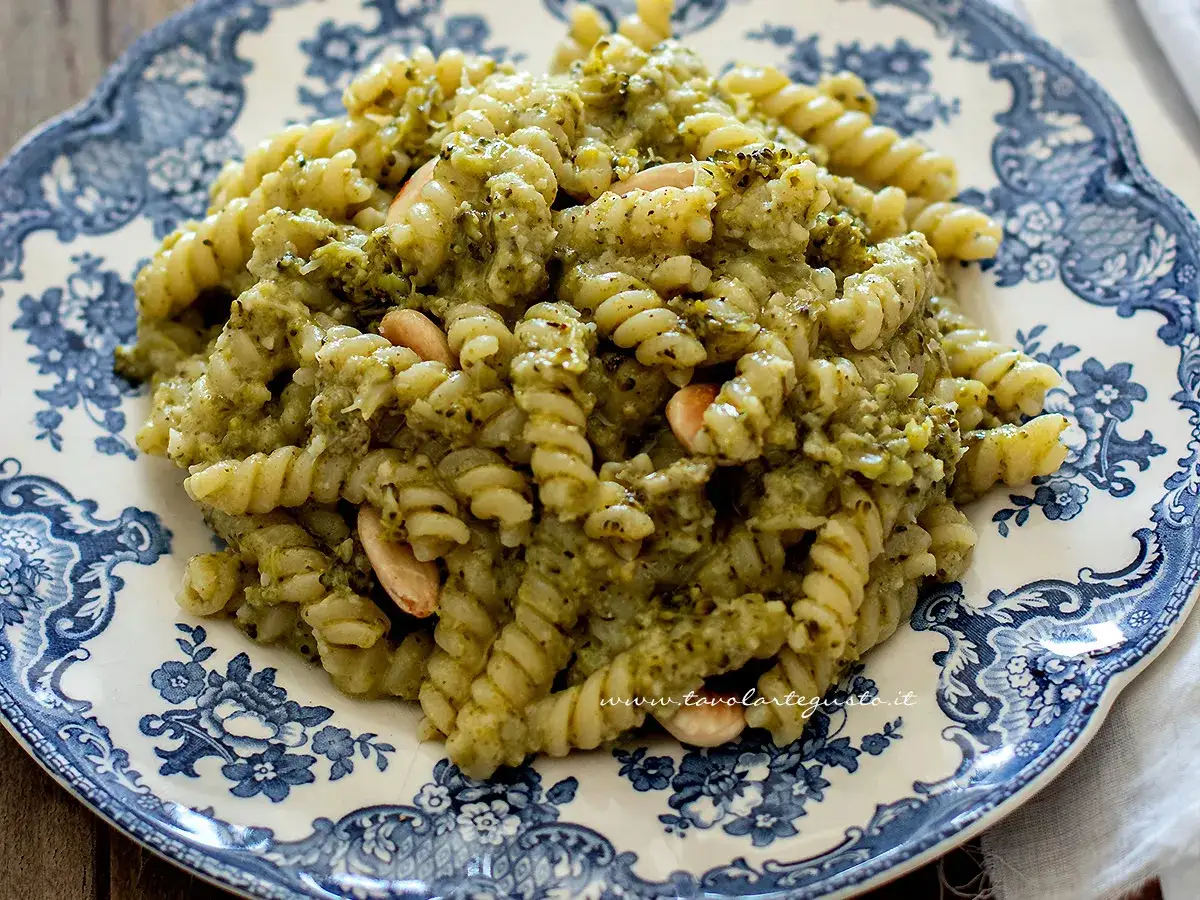 Fusilli conditi con un cremoso sugo di pasta con i broccoli e mandorle, serviti su un piatto decorato.