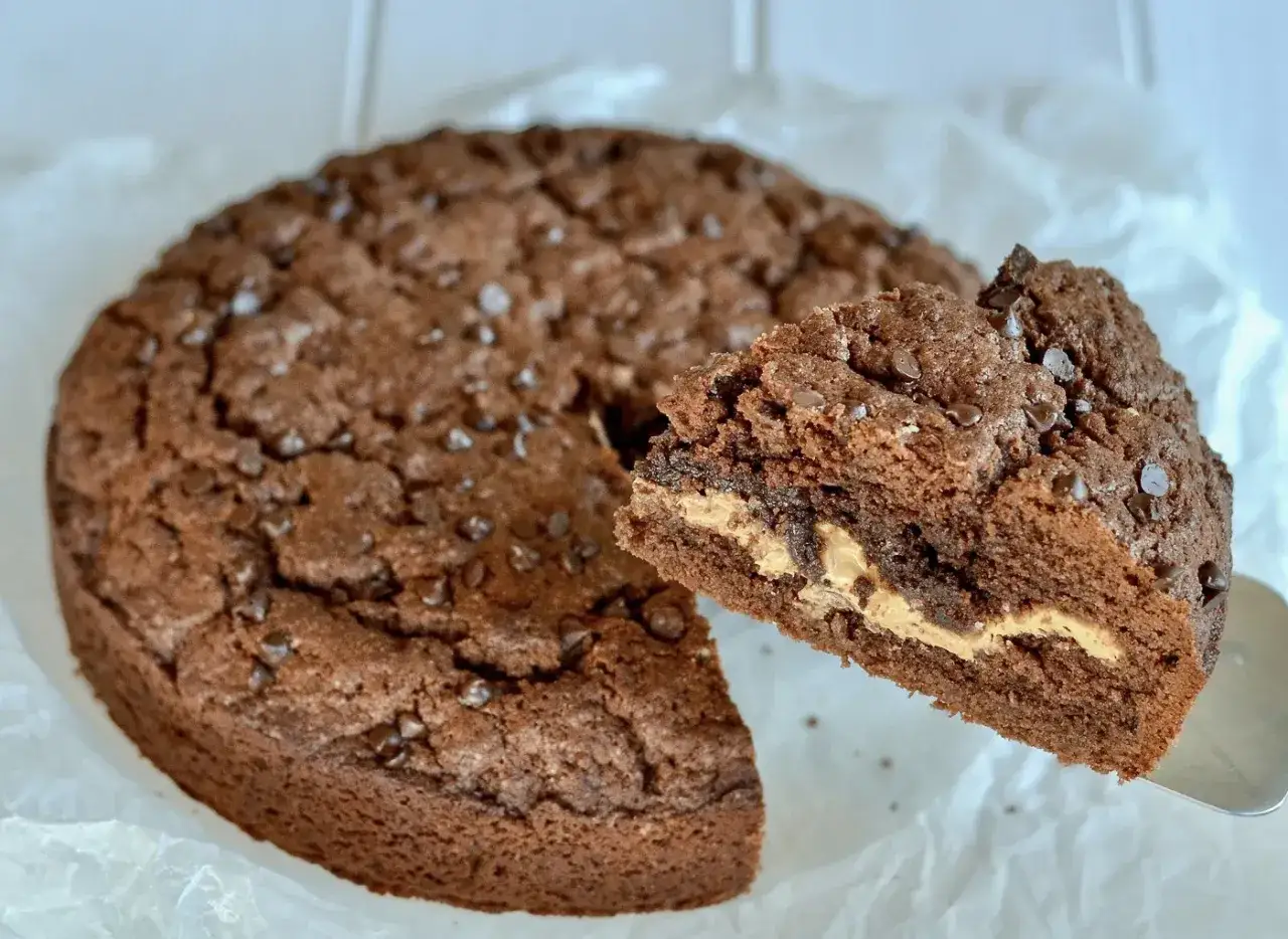 Torta al cioccolato con cuore morbido di crema di nocciole e gocce di cioccolato. Una fetta mostra il ripieno goloso.
