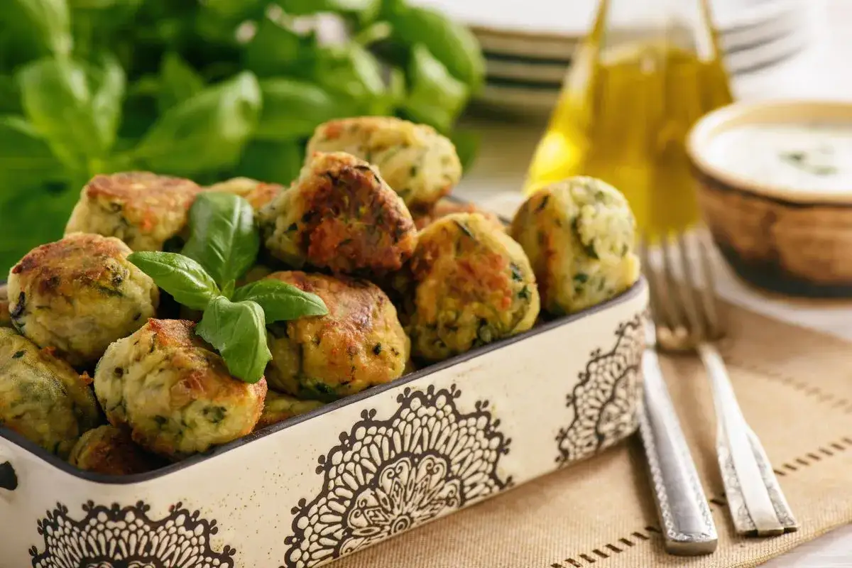Deliziose polpette di verdure al forno, dorate e profumate, guarnite con basilico fresco. Un piatto leggero e gustoso.
