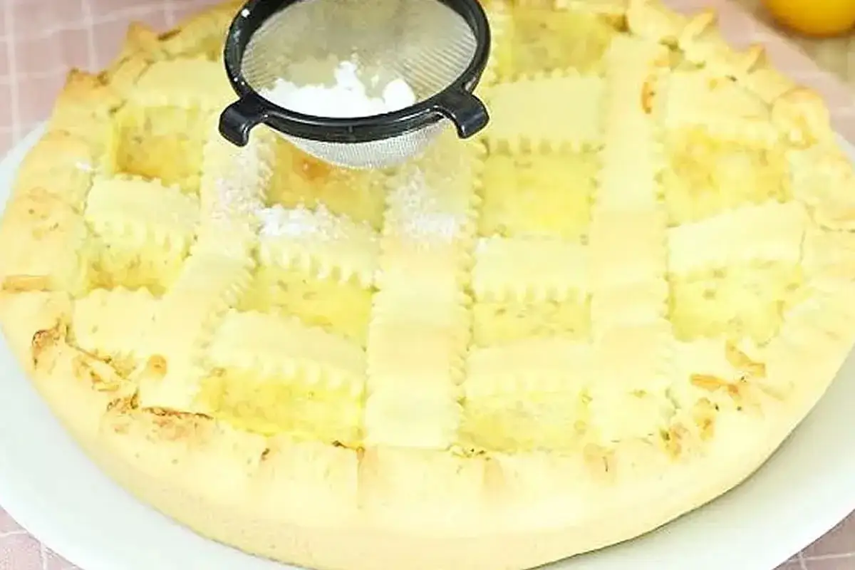 Crostata con crema pasticcera, con una griglia di pasta frolla e una spolverata di zucchero a velo.