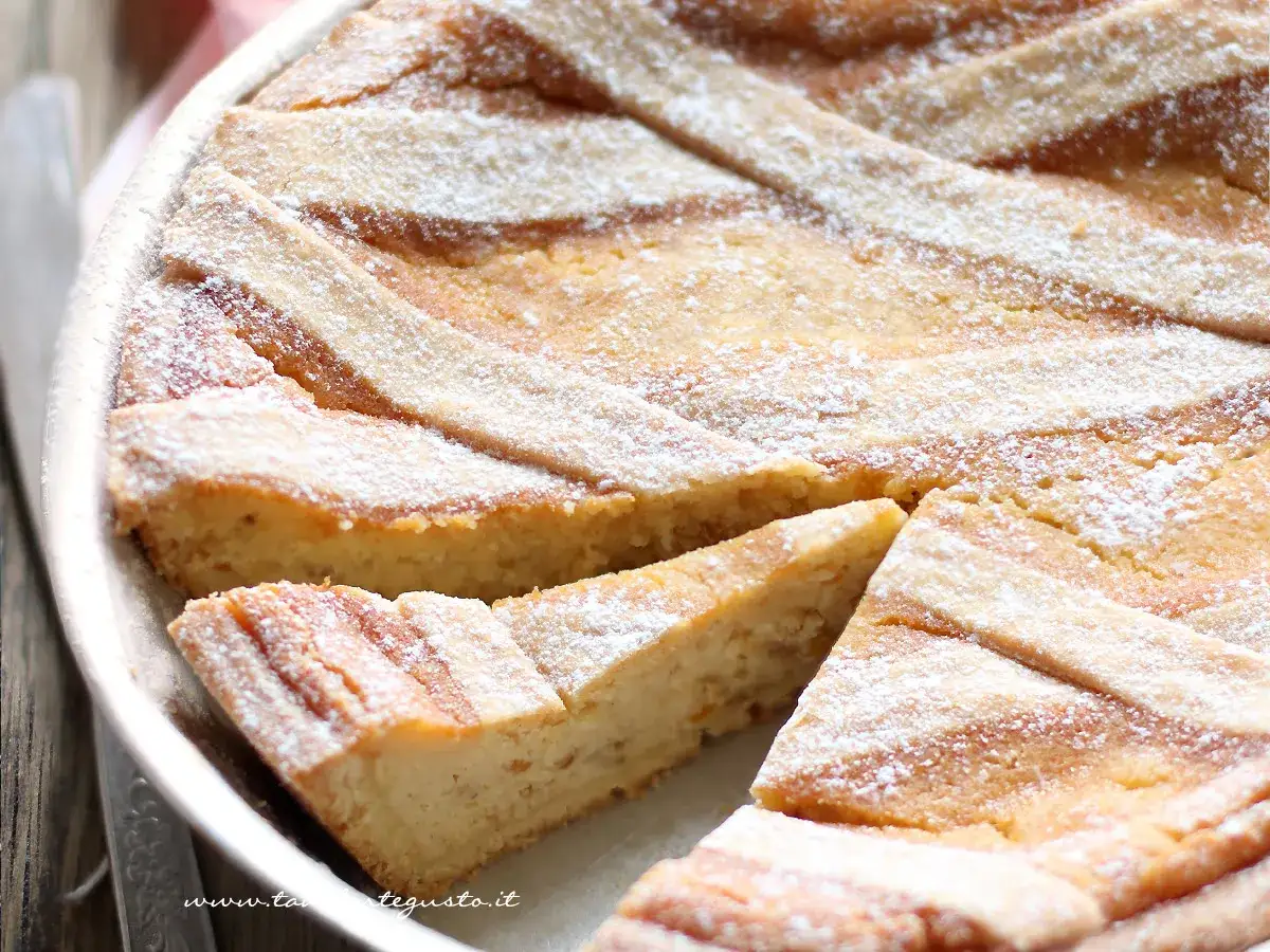 La ricetta pastiera napoletana: una torta dorata con strisce di pasta frolla e zucchero a velo, pronta per essere gustata.