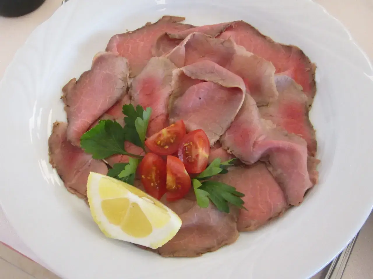 Fette sottili di roast beef, guarnite con pomodorini, prezzemolo e spicchio di limone. Una deliziosa ricetta da provare!