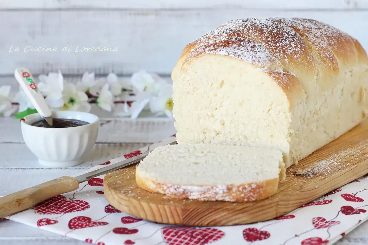 Un soffice pan brioche dolce, spolverato di zucchero a velo, pronto per essere gustato con marmellata.