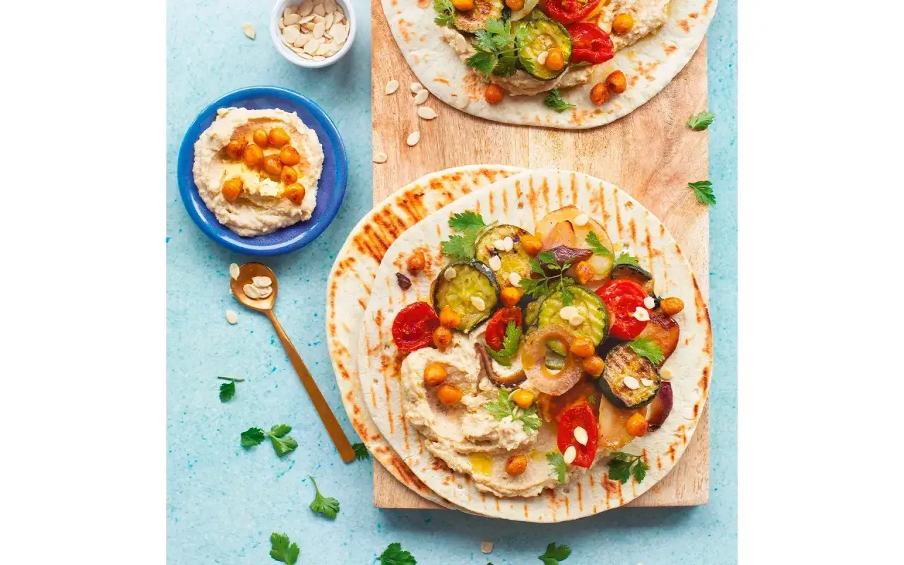 Piadina di ceci con verdure grigliate e hummus. Un piatto colorato e gustoso, perfetto per un pasto leggero e nutriente.