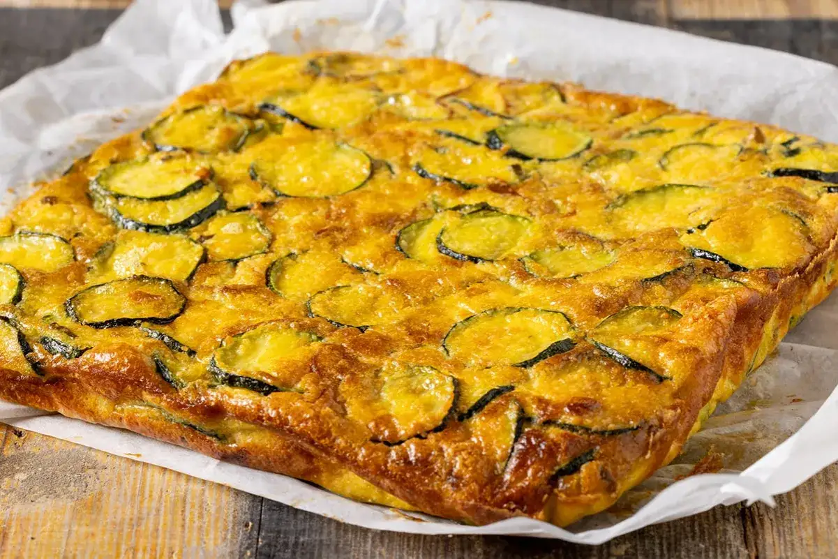 Frittata di zucchine al forno, dorata e invitante, con fette di zucchine ben distribuite sulla superficie.