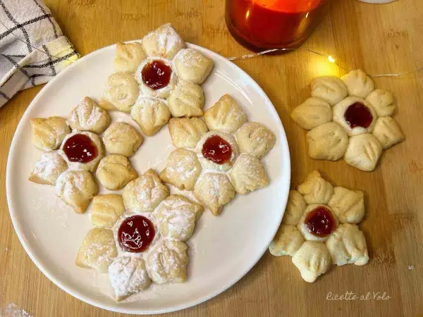 Deliziosi biscotti con marmellata a forma di fiore, spolverati di zucchero a velo, pronti per essere gustati.