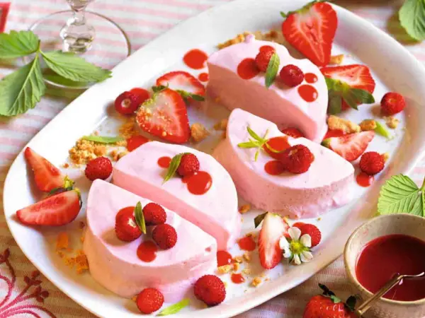 Delizioso semifreddo alle fragole, guarnito con fragoline di bosco, salsa rossa e foglioline verdi. Un dolce estivo perfetto.