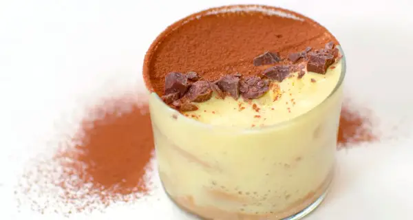 Un bicchiere di tiramisù, con cacao e scaglie di cioccolato. Perfetto per scoprire come si fa il tiramisù.